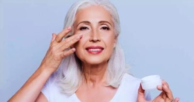 Mulher 60+ passando creme rejuvenescedor no rosto (Foto Reprodução/Freepik)