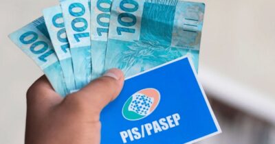 Homem segurando notas de cem reais e cartão do PIS/Pasep (Foto: Reprodução / Internet)