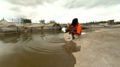 Homem pegando água suja para beber (Foto: Divulgação / Record)