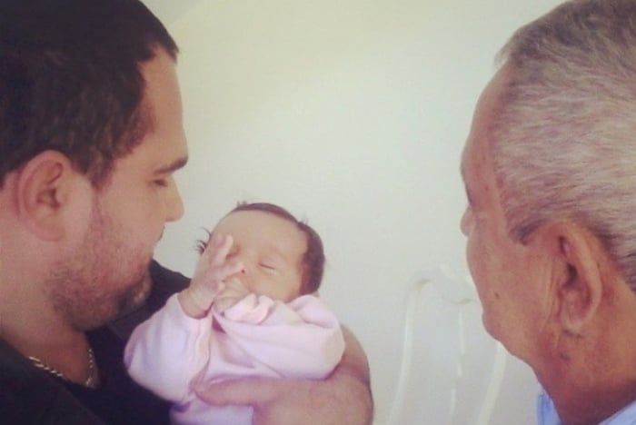 Luciano segurando a neta nos braços ao lado de seu pai, Francisco 