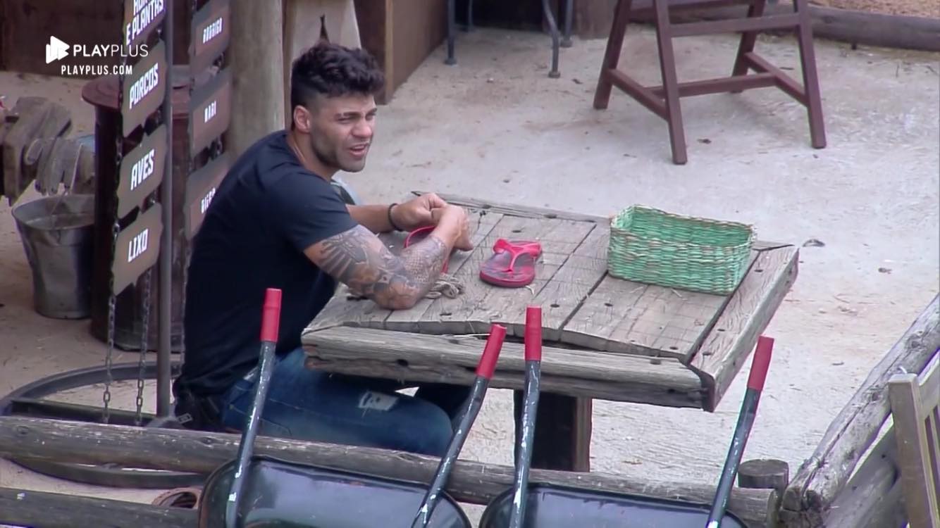 Netto conserta chinelo de Lucas Viana em A Fazenda (Reprodução: PlayPlus/Record TV)