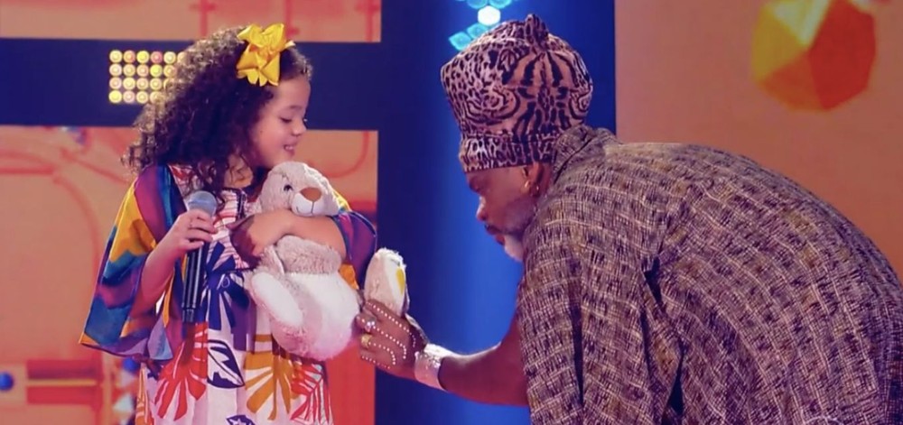 Carol Breder e Carlinhos Brown no The Voice Kids deste domingo (26); candidata levou coelho da sorte (Foto: Reprodução)