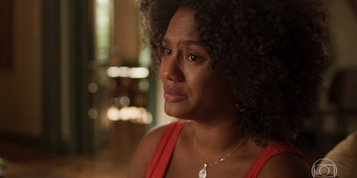 Camila, em cena da novela Amor de Mãe, está usando uma medalha de prata, regata vermelha e é negra