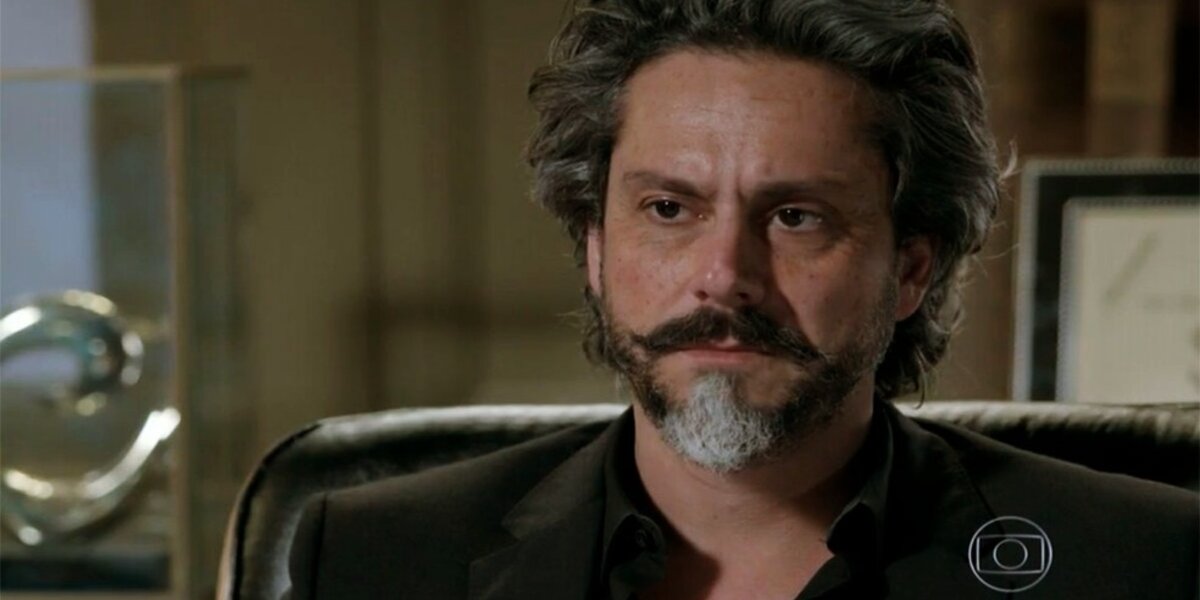 José Alfredo, homem mais velho com barba e cabelos grisalhos e preto com terno preto em cena da novela Império