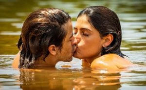 Jove (Jesuita Barbosa) beija Guta (Julia Dalavia) na novela 'Pantanal': nus com a mão no bolso (Foto: Reprodução / Globo)