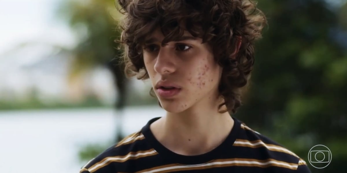 Rudá dentro da novela Travessia usando camisa listrada ao ar livre