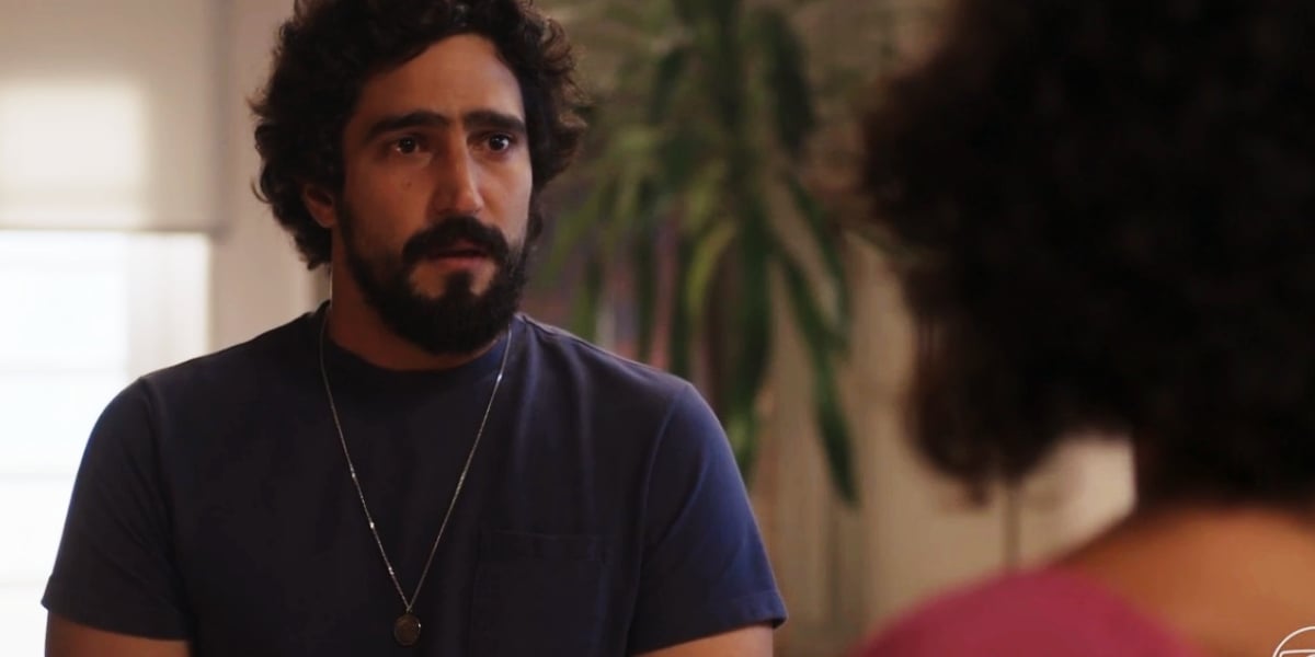 Tertulinho usando camisa azul de manga curta, barba e cabelo preto em cena da novela Mar do Sertão