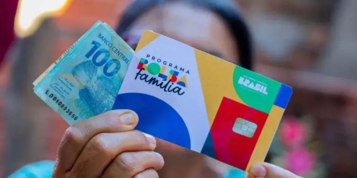 Mulher recebendo o pagamento do Bolsa Família com o dinheiro em mãos e o cartão do programa social - Foto Reprodução Internet