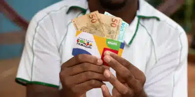 Homem segurando cartão do Bolsa Família e dinheiro  (Foto: Reprodução,  Pronatec)