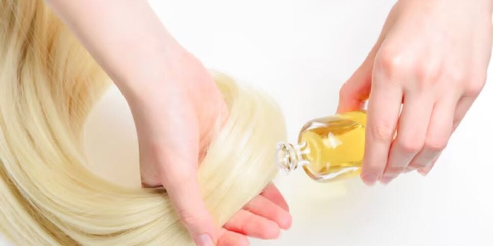 Mulher passando óleo nas pontas do cabelo (Foto: Reprodução / Freepik) 