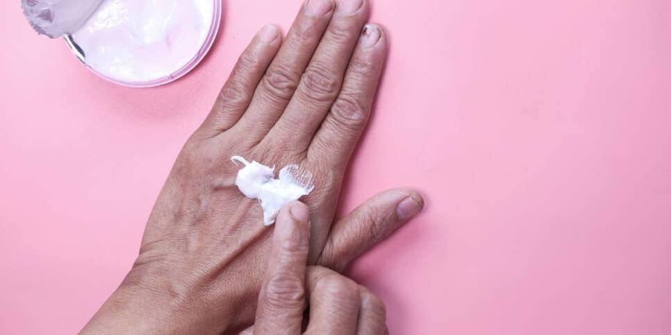 Mulher passando creme na mão (Foto: Reprodução / Canva)