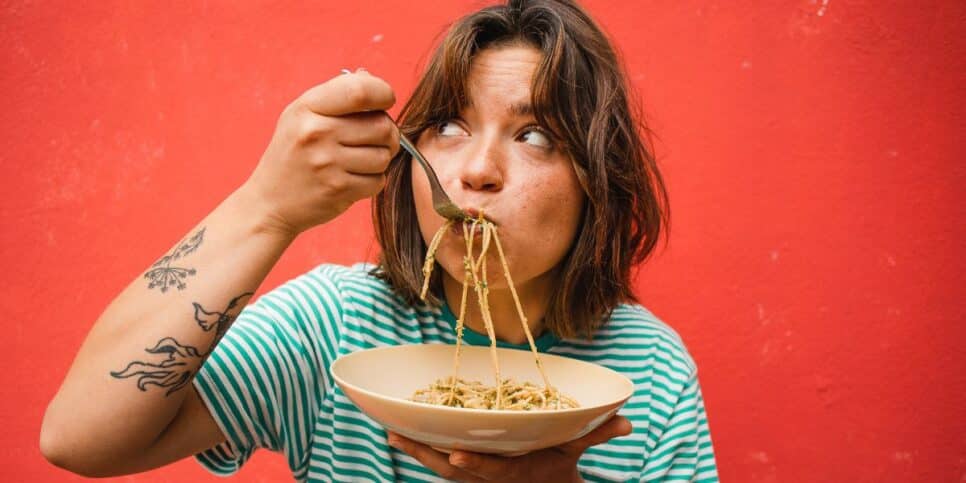 Mulher comendo macarrão (Foto: Canva)