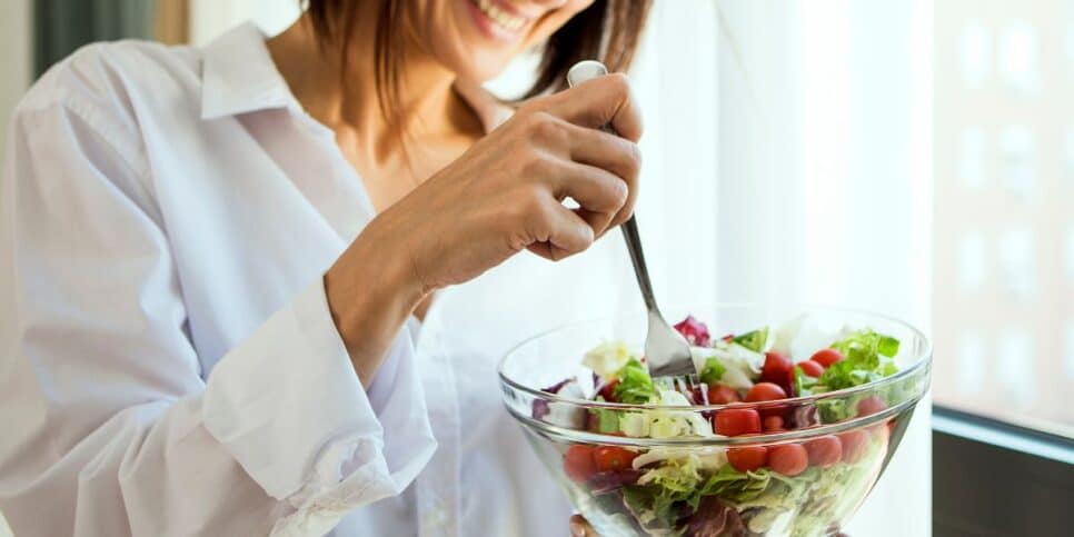 Mulher comendo legumes (Foto: Canva)