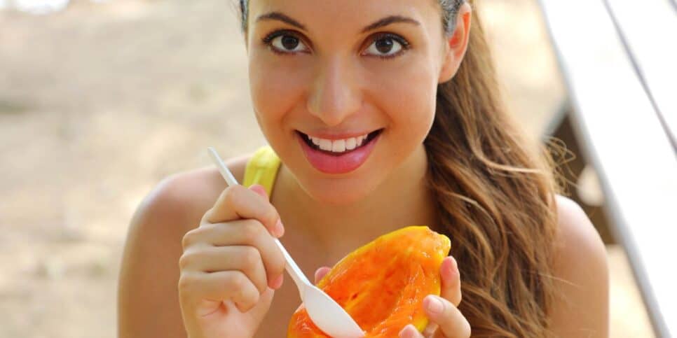 Mulher comendo mamão (Foto: Canva)