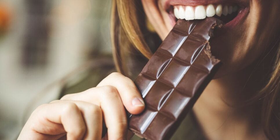 Mulher comendo chocolate (Foto: Canva)