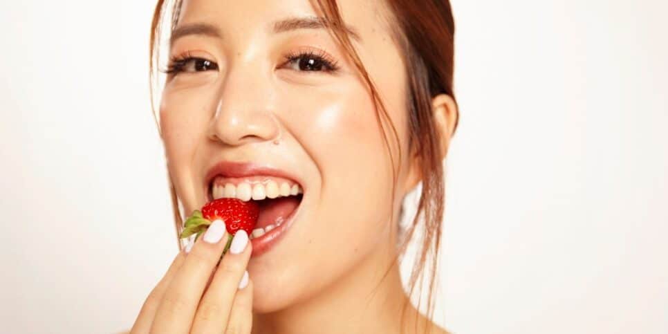 Mulher comendo morango (Foto: Canva)