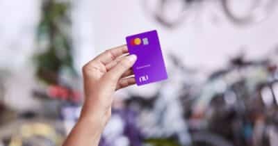 Mulher segurando cartão de crédito do Nubank (Foto: Reprodução / site oficial fintech)