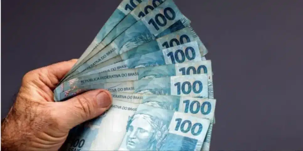 Homem segurando notas de cem reais (Foto: Canva)