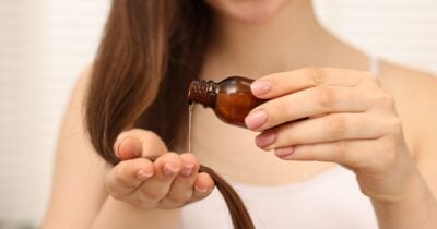 Mulher passando óleo no cabelo fino (Foto: Canva)