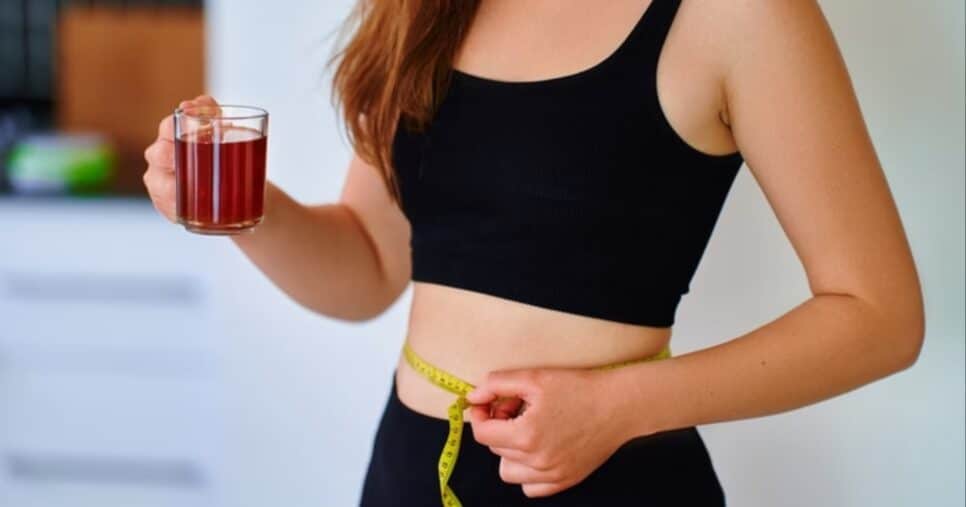 Imagem de uma mulher segurando um chá natural e medindo a cintura com uma fita (Foto: Reprodução/ Internet)