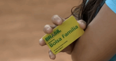 Mulher segurando cartão do Bolsa Família (Foto: Reprodução / Globo)