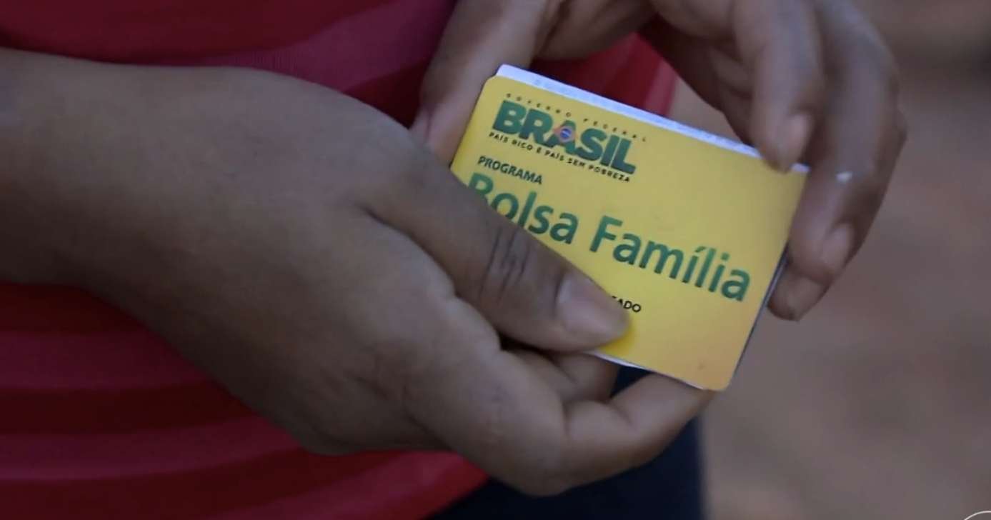 Pessoa segurando cartão do Bolsa Família (Foto: Reprodução / Globo)