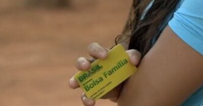 Mulher segurando cartão do Bolsa Família (Foto: Reprodução / Globo)