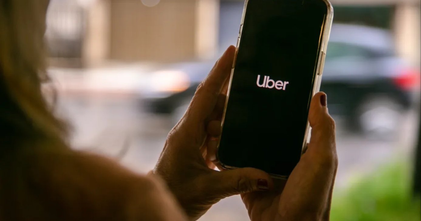 Mulher segurando o celular com o aplicativo da Uber (Foto: Reprodução/ Internet)