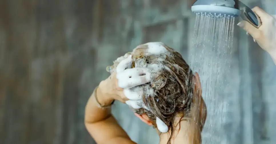 Mulher lavando o cabelo com shampoo (Reprodução: Canva)
